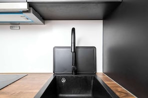 Eine Küche mit einem schwarzen Spülbecken, einem Wasserhahn und einer eingebauten Dunstabzugshaube.