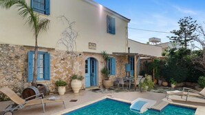 Una villa con piscina, mobiliario exterior y fachada de piedra.