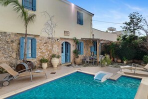 Eine Villa mit Pool, Sitzgelegenheiten im Freien und einer Steinfassade.