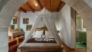 Un dormitorio con cama con dosel, un banco de madera, un tocador con espejo y un armario verde.