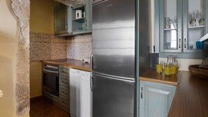 Una cocina con un refrigerador de acero inoxidable, lavavajillas, horno y pileta. Posee un salpicadero de azulejos y un arco de piedra.
