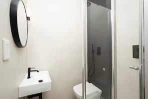 Ein Badezimmer mit weißem Waschbecken, Toilette und einer Duschkabine.