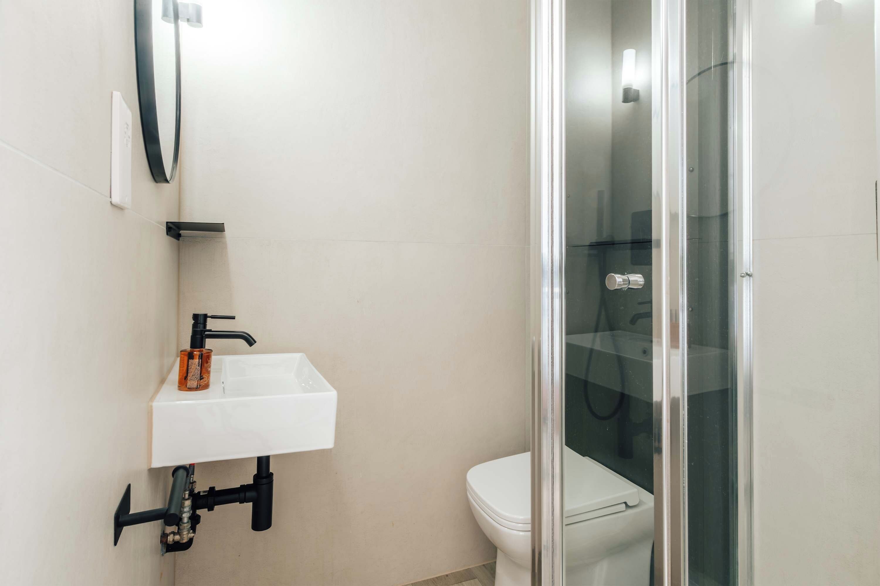 Een badkamer met een witte wastafel, een toilet en een douchecabine met glazen wanden.