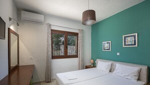 A bedroom with a bed, a window, an air conditioning unit, a lamp, and two framed pictures on the wall. - Villa Portokalia - Two Bedroom Villa, Sleeps 4 (Platanias)
