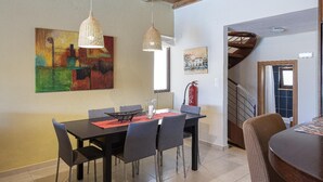 A dining area with a table, chairs, pendant lights, and artwork on the walls. - Villa Portokalia - Two Bedroom Villa, Sleeps 4 (Platanias)