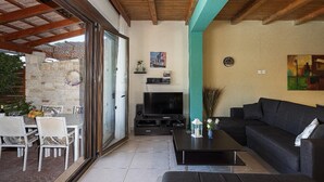 An open-plan living area with a TV, sofa, and dining table. - Villa Portokalia - Two Bedroom Villa, Sleeps 4 (Platanias)