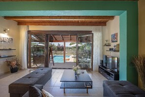 A living room with a pool, sofas, a coffee table, and a TV. - Villa Portokalia - Two Bedroom Villa, Sleeps 4 (Platanias)