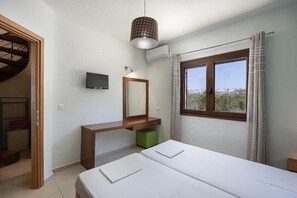 Ein Schlafzimmer mit einem Bett, einem Holztisch, einem Spiegel, einem Fernseher und einem Fenster mit Vorhängen.