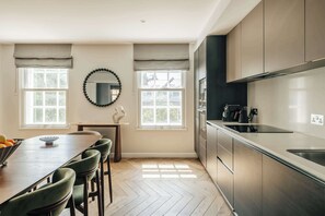 A modern kitchen with a dining area, large windows, and a herringbone floor pattern. - Premium 3-Bed Belgravia | Sloane Square (London)