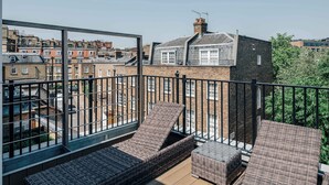 A balcony with wicker furniture, a view of neighboring buildings, and a clear sky. - Premium 3-Bed Belgravia | Sloane Square (London)