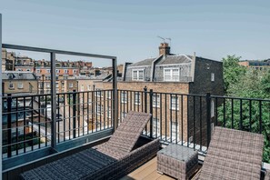 A balcony with wicker furniture, a view of neighboring buildings, and a clear sky. - Premium 3-Bed Belgravia | Sloane Square (London)