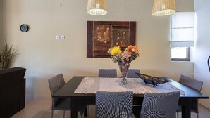 Ein Essbereich mit Tisch, Stühlen, einer Blumenvase und zwei Hängelampen.