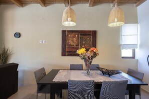 A dining area with a table, chairs, a vase of flowers, and two hanging lights. - Villa Lemonia - Two Bedroom Villa, Sleeps 4 (Platanias)