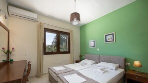 Ein Schlafzimmer mit Bett, Schreibtisch, Fenster und einer grünen Wand.