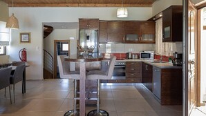 Eine moderne Küche mit Holzausstattung, einer zentralen Kochinsel und einem Essbereich mit einem Stuhl.