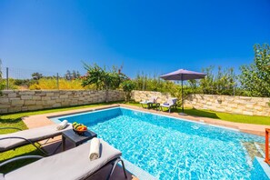 A swimming pool with lounge chairs and a stone wall. - Villa Lemonia - Two Bedroom Villa, Sleeps 4 (Platanias)