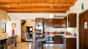 A modern kitchen with wooden cabinets, stainless steel appliances, and a dining area with a table and chairs. - Villa Mandarin - Two Bedroom Villa, Sleeps 4 (Platanias)