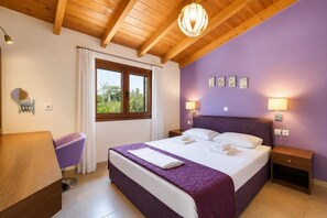 A bedroom with a bed, bedside tables, a nightstand, a window with curtains, a hanging light fixture, and wall art. - Villa Mandarin - Two Bedroom Villa, Sleeps 4 (Platanias)