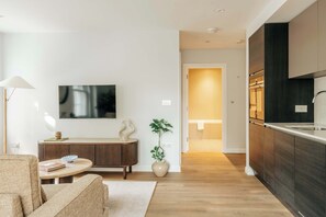 Ein modernes Wohnzimmer mit einer Couch, einem Couchtisch, einem Fernseher und einer dekorativen Vase.