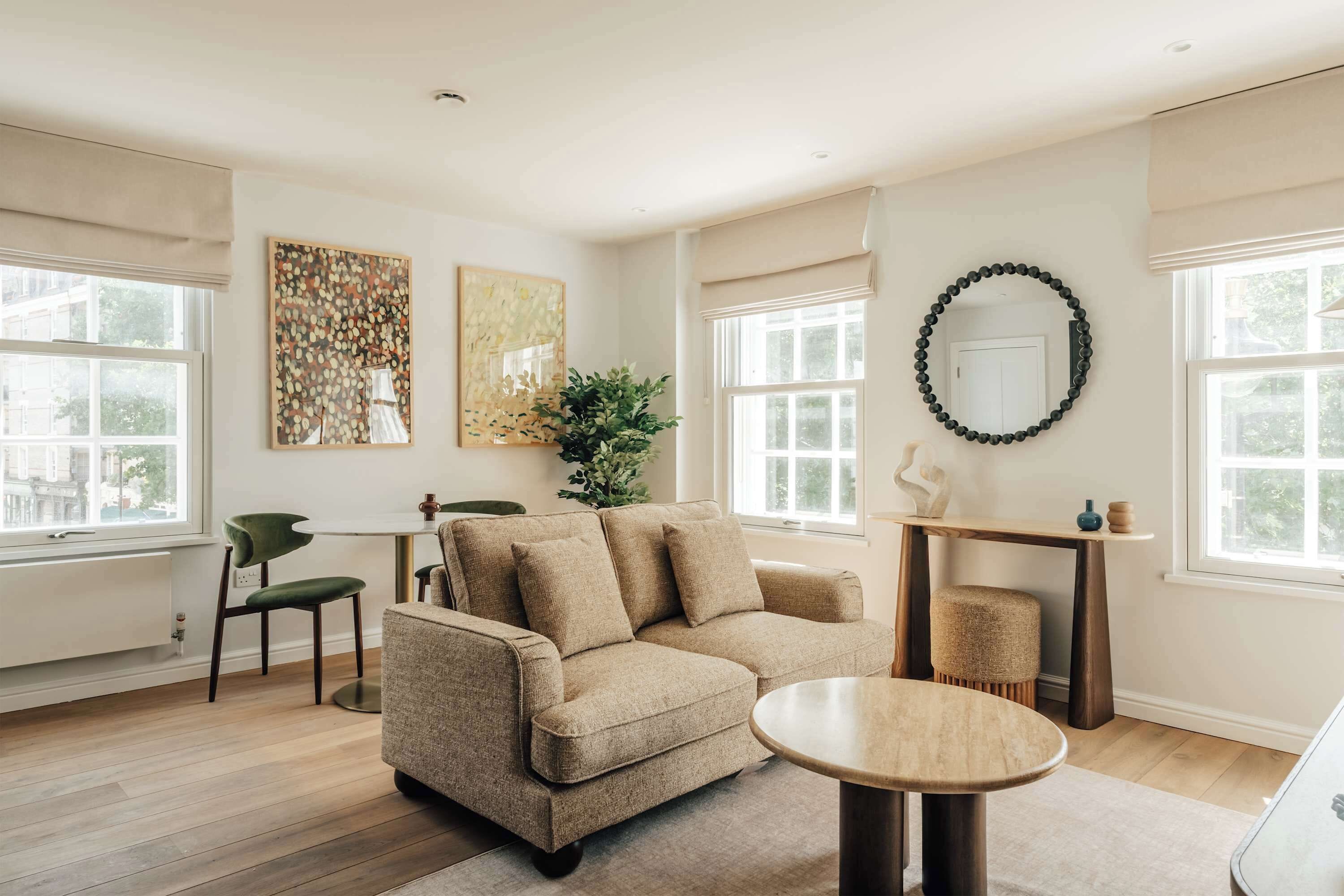 A living room with a beige sofa, a round coffee table, and artwork on the walls.