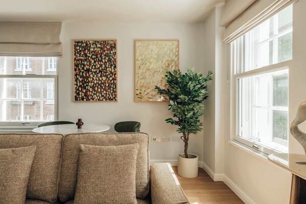 Ein modernes Wohnzimmer mit einer Sofagarnitur, einem runden Tisch und zwei an der Wand befestigten Kunstwerken.