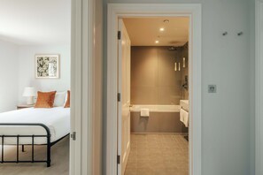 A bedroom with a bed, a nightstand, and a wall-mounted lamp. - Elegant 1-Bed Belgravia | The Bourne by Nestor (London)