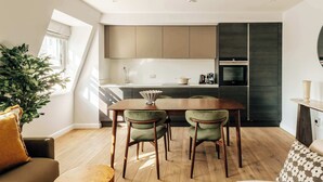 Een moderne keuken met een eethoek, houten vloeren en een groot raam.