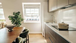 Een moderne keuken met een eethoek, een raam met zonwering en een potplant.