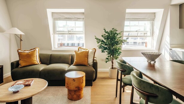 Een moderne woonkamer met een bank, een salontafel, een eettafel en een potplant.