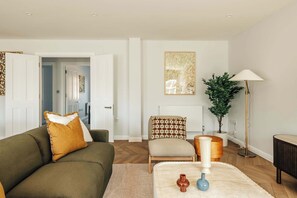 Ein Wohnzimmer mit Sofa, Sessel, Stehlampe und einem Blumentopf.