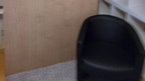 En receptionsdisk med en spegel, en krukväxt och en svart stol.