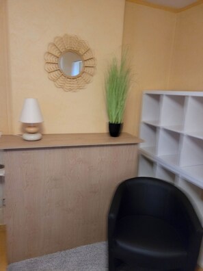 A reception desk with a mirror, a potted plant, and a black chair. - Quiet apartment near amenities, located on a cul-de-sac (Aurillac)