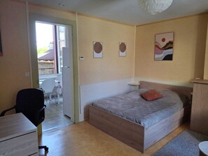 A bedroom with a bed, a desk, a chair, and a small table. - Quiet apartment near amenities, located on a cul-de-sac (Aurillac)