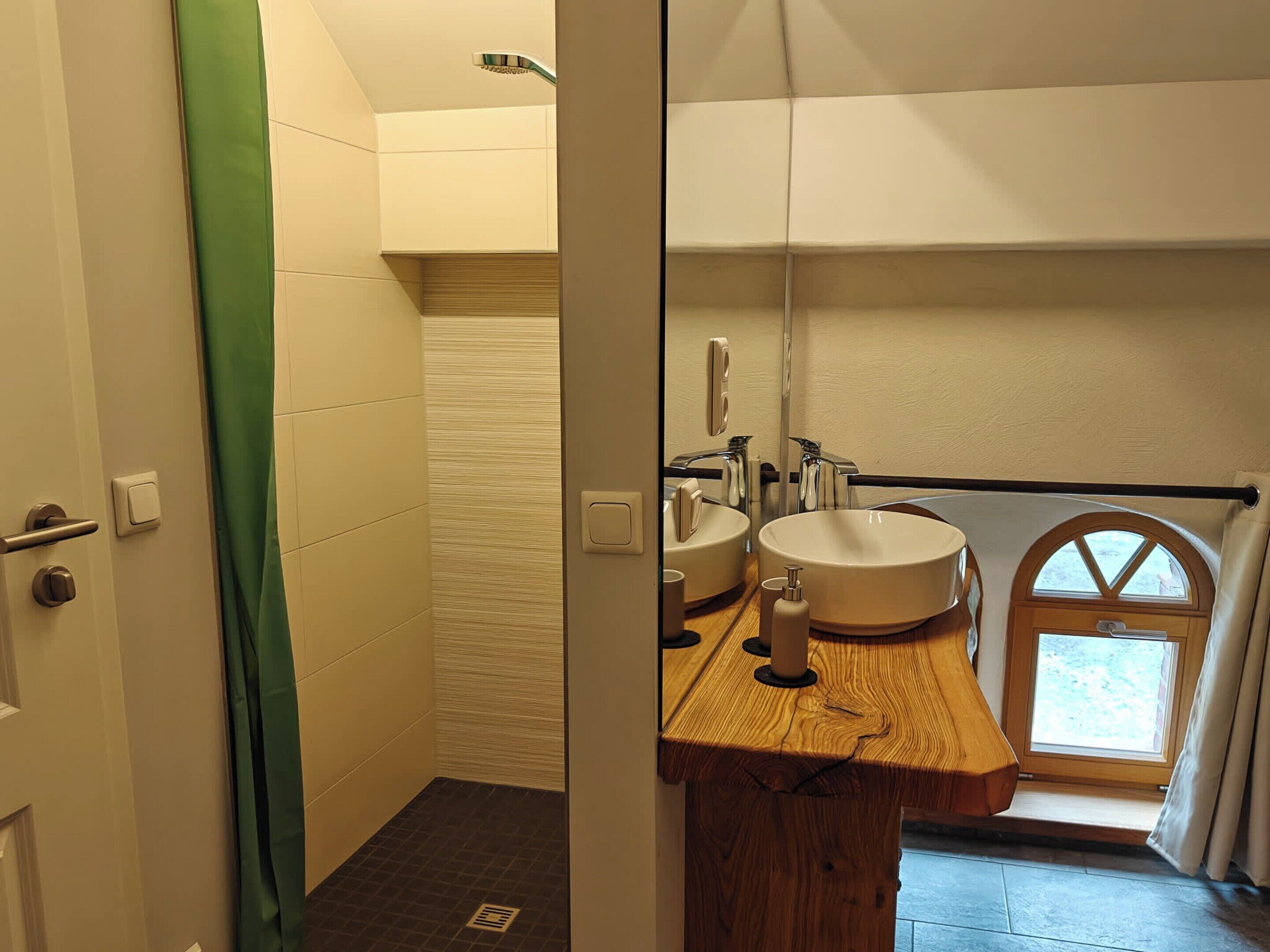 Un baño con tocador de madera, dos lavamanos, un espejo y una ventana con vistas.