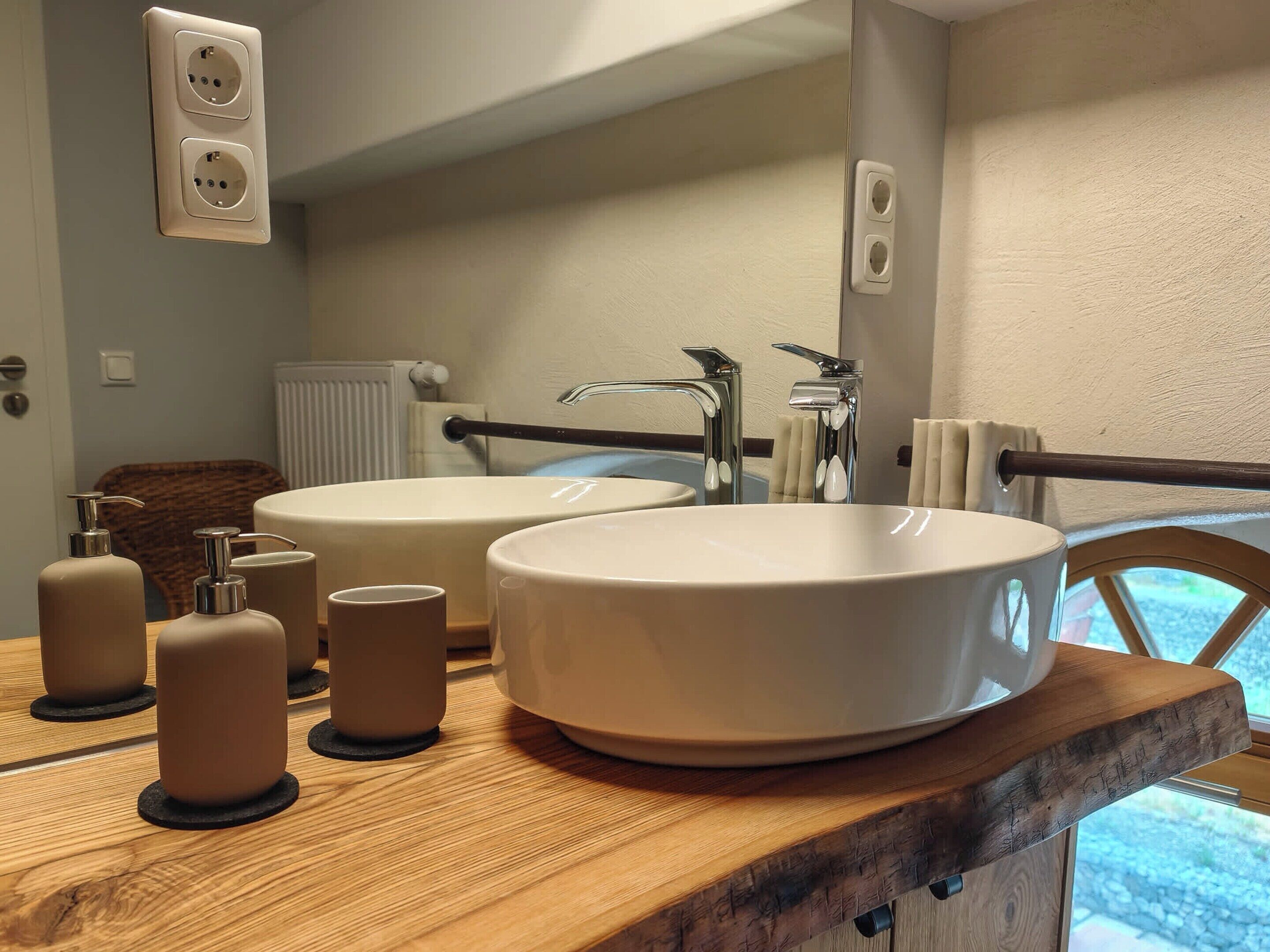 Une salle de bain avec deux lavabos, un meuble-lavabo en bois, un porte-serviettes et une fenêtre donnant sur un paysage agréable.