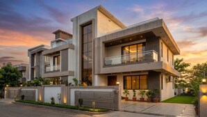 Une maison moderne à deux étages, dotée d’un balcon, de grandes fenêtres et d’une pelouse bien entretenue.