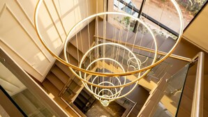 Un intérieur moderne avec un escalier en colimaçon, des rampes de verre et une vue par les fenêtres.