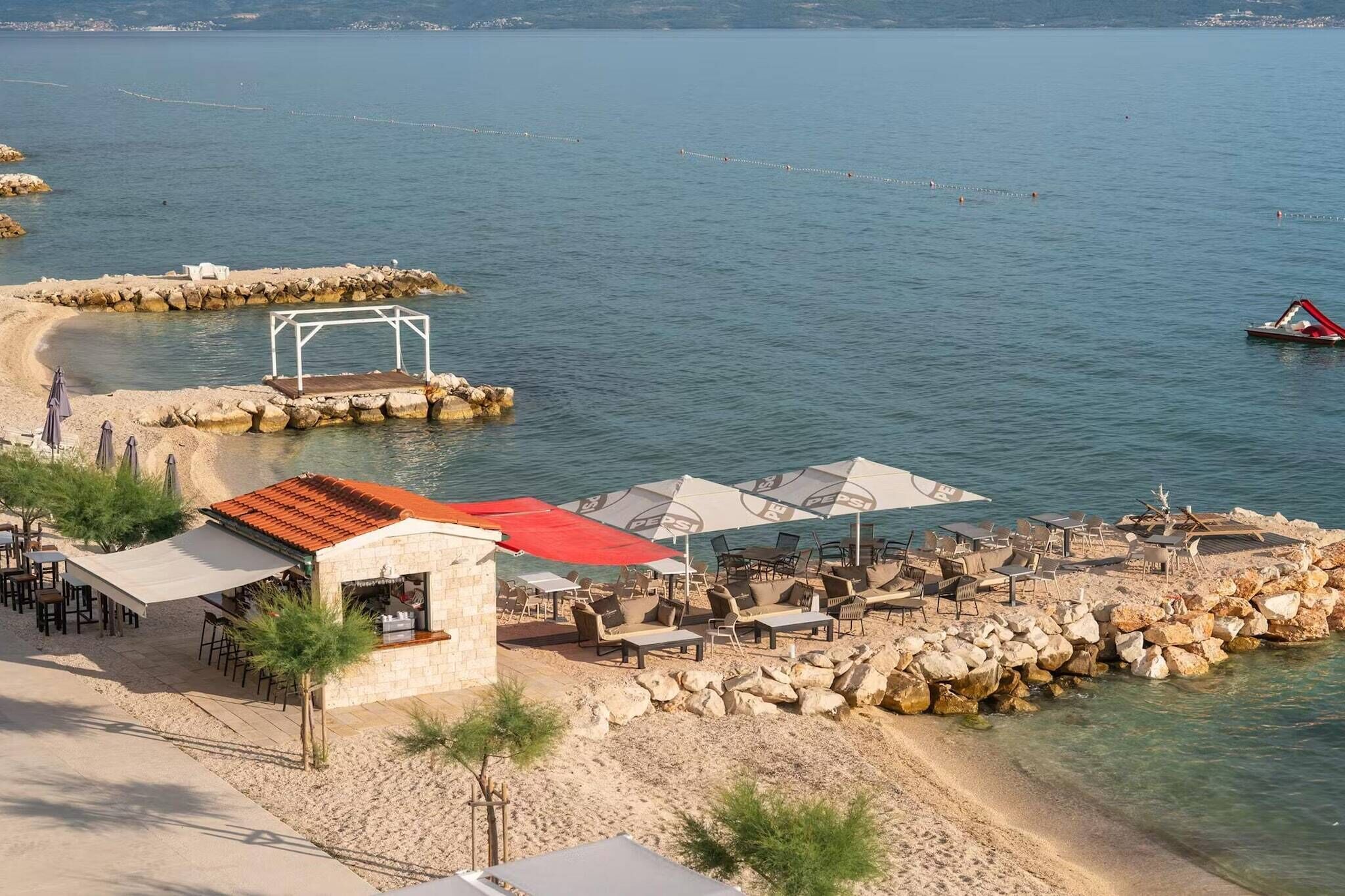 Een restaurant aan het strand met terras, een gebouw van natuursteen en uitzicht op zee.