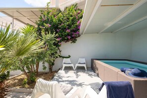 A sunlit outdoor area with a pool, white lounge chairs, and a small garden with a tree and flowering plants. - Beachfront Villa with Spa Pool (Podstrana)