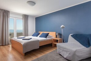 Ein Schlafzimmer mit Bett, Nachttisch, Lampe und einem Sessel.