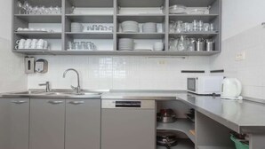 Eine moderne Küche mit grauen Schränken, einem Geschirrspüler, einer Mikrowelle und einem Wasserkocher.