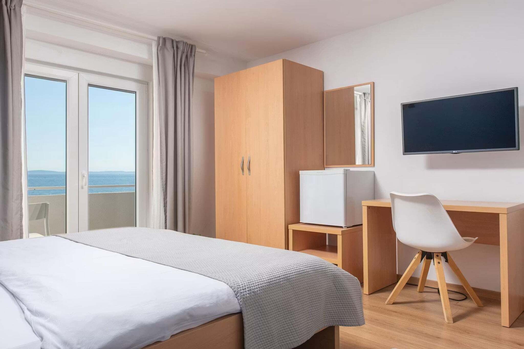 Une chambre d’hôtel comprenant un lit, un bureau, une chaise, une télévision et une armoire.