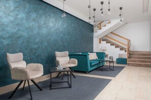 A modern living room with a teal accent wall, a staircase, and a green sofa. - Beachfront Villa with Spa Pool (Podstrana)