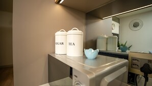 Un plan de travail de cuisine avec deux récipients blancs étiquetés « SUCRE » et « THÉ », un bol en céramique bleue et une cuisinière moderne.