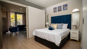 Une chambre à coucher moderne avec un lit, des tables de chevet, un bureau et une chaise.