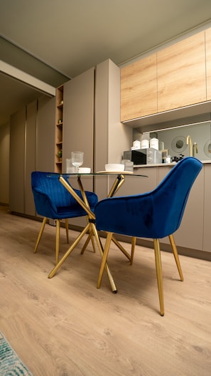 Eine moderne Küche mit zwei blauen Stühlen, einem Glastisch, Holzschränken und einer Mikrowelle.