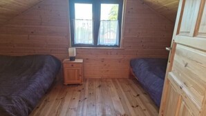 A small, wooden-paneled room with two beds, a nightstand, and a window. - Holiday home with a terrace, close to the beach (Sianozety)