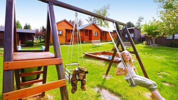 A wooden swing set in a grassy yard with a house in the background. - Holiday home with a terrace, close to the beach (Sianozety)