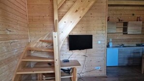 A wooden interior with a staircase, a mounted television, and a kitchen area. - Holiday home with a terrace, close to the beach (Sianozety)