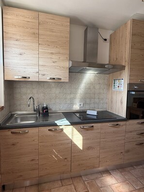 A kitchen with wooden cabinets, a stainless steel sink, and a modern stove. - "Corte Magnolia Lazise" Vacation Home, Between the Thermal Springs and Lake Garda (Colà)